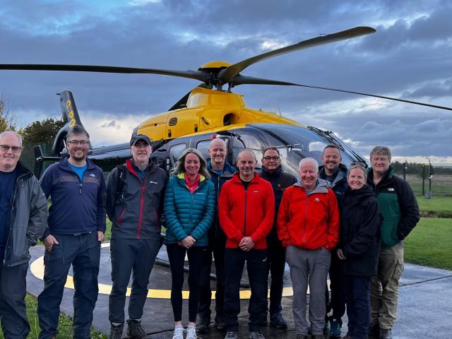 A NPAS North West team of staff standing in front of the NPAS Barton police helicopter