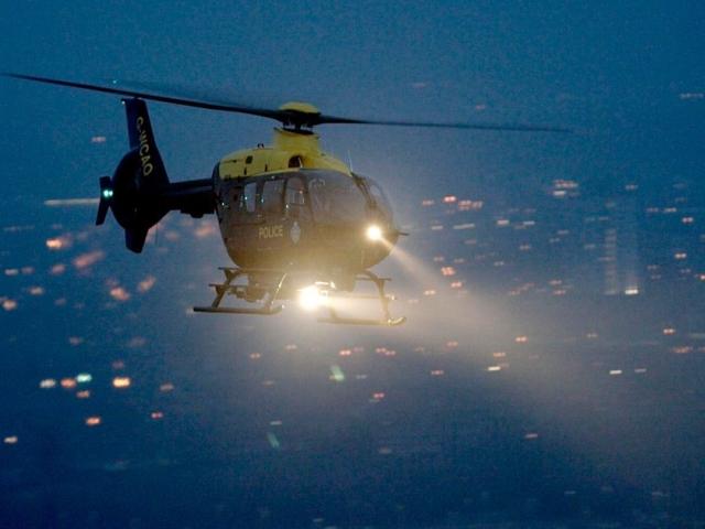 NPAS helicopter flying at night with NightSun light illuminated